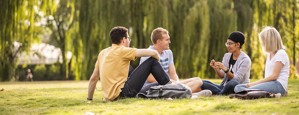 Students chatting while relaxing on a lawn on the ANU campus.