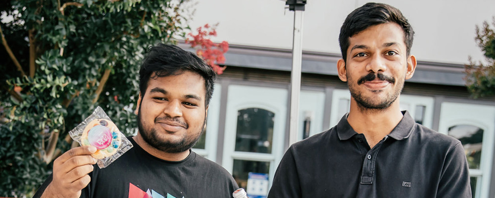 Nakul and a friend hand out drinks and cookies at an ANU stall.