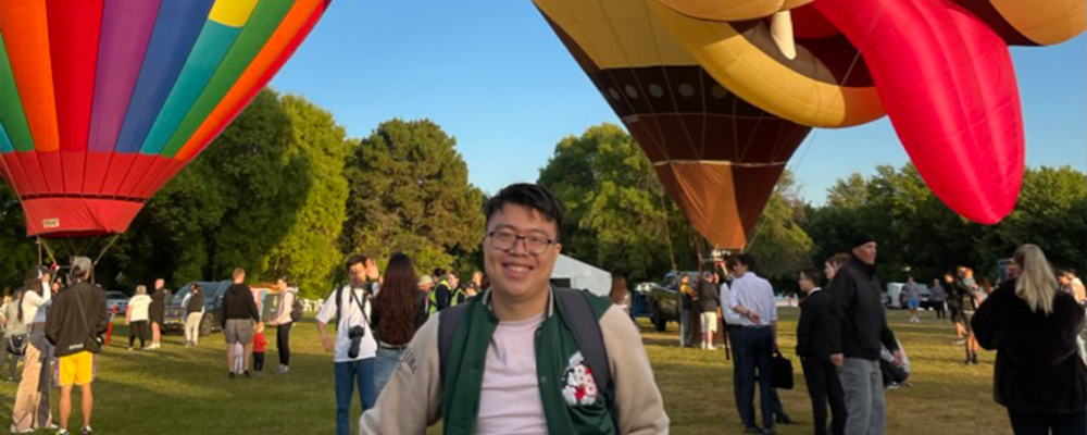 Trevin stands in front of several hot air balloons as part of Canberra's Enlighten Festival.