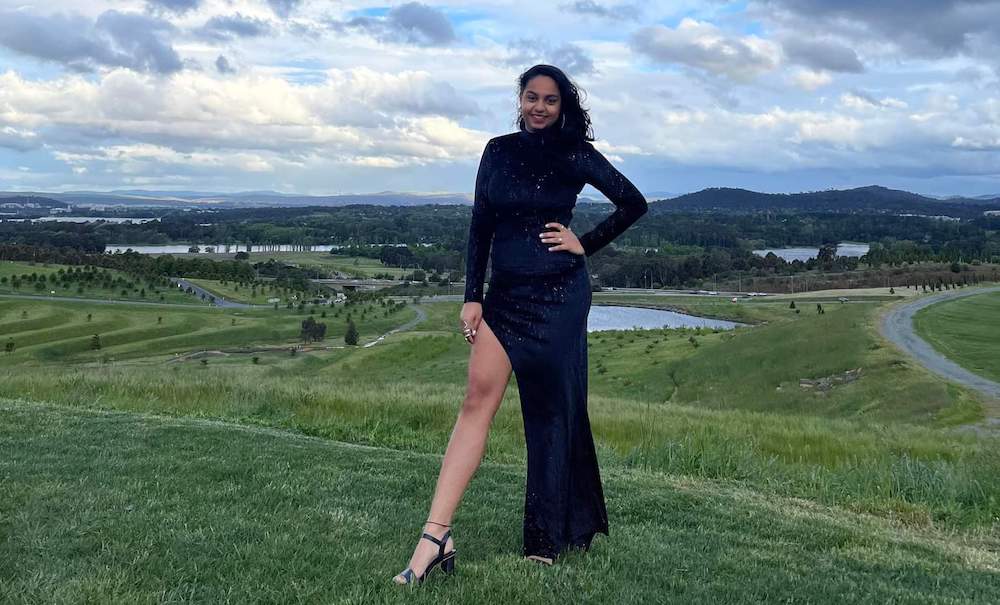  Priya, wearing a formal dress, poses joyfully for a photo.