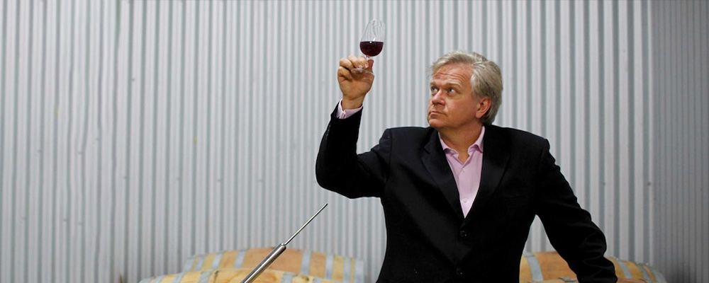 Brian looks at a glass of red wine at his vineyard.